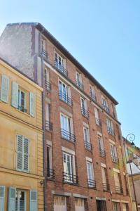 un gran edificio de ladrillo con ventanas en una calle en SweetHomeVersailles 5mn walk from the Palace en Versalles