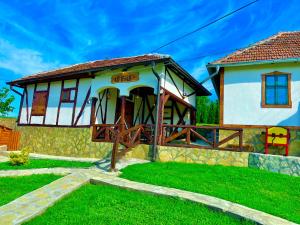 a small house with a wooden porch in a yard at Etno selo Stanojevic in Boljevac