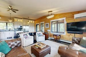 a living room with leather furniture and a kitchen at Fox Lane Retreat in White River Junction