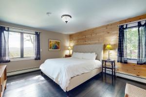 a bedroom with a large bed and two windows at Fox Lane Retreat in White River Junction