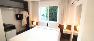 1 dormitorio con cama blanca y ventana en Parador Búzios Boutique Hotel en Búzios