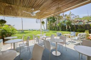 a group of tables and chairs under a pavilion at Perla de la Playa Beachfront Hotel in Tamarindo