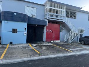 ein weißes Gebäude mit einer roten Tür und einer Treppe in der Unterkunft Group Unit Great Location in San Juan