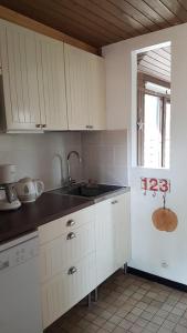 ラカノーにあるVitanova Sunset Lacanau Océanの白いキャビネット、シンク、窓付きのキッチン