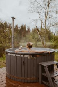 a woman laying in a hot tub with a cat in it at River Cabin in Inciems