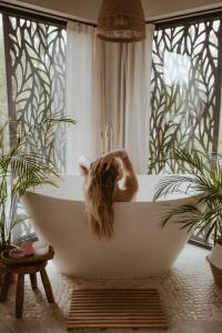 a woman sitting in a bath tub in a bathroom at River Cabin in Inciems