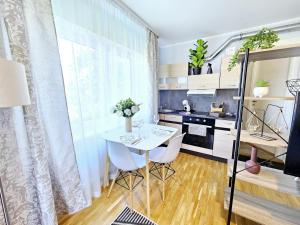 Cozy apartment close to the sea! في تالين: مطبخ صغير مع طاولة بيضاء وكراسي