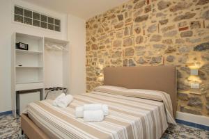 un lit dans une chambre avec un mur en pierre dans l'établissement Belvedere Rooms, à Marina di Camerota