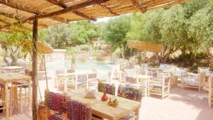 un groupe de tables et de chaises en face d'une piscine dans l'établissement Paradis Nomade, à Azrarag