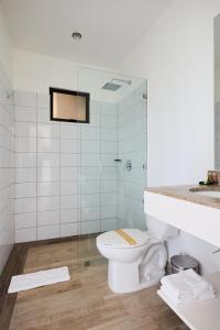 a bathroom with a toilet and a glass shower at Hotel Perla de la Playa in Tamarindo