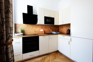 una cocina con armarios blancos y electrodomésticos negros en Royal Residences Vienna, en Viena