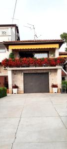 a building with a garage with red flowers on it at Apartment near the center - Nada in Malinska