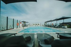 una gran piscina con mesas y sillas en Hotel Málaga Nostrum Airport en Málaga