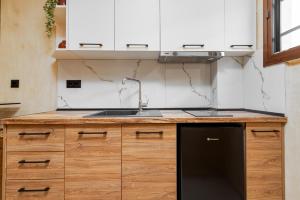 a kitchen with white cabinets and a black dishwasher at Odyssey Accommodation - Apartments in Pefkochori