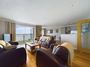 a living room with couches and a table and a television at Cosy 3 bedroom apartment in central Portrush with sea views in Portrush