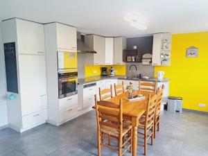a kitchen with a wooden table and yellow walls at *Au Refuge Ardennais* in Bertogne