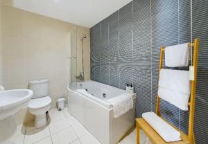 a bathroom with a tub and a toilet and a sink at Cosy 3 bedroom apartment in central Portrush with sea views in Portrush +18 photos