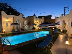 una piscina con sillas y sombrillas por la noche en Konaki Apartments, en Máleme