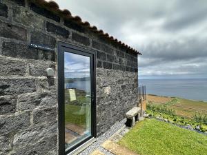 a door to a stone building with a view of the ocean at João de Oliveira - casas de campo in Santo António