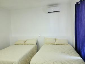two beds in a small room with blue curtains at JESAVI Suites in Monterrey