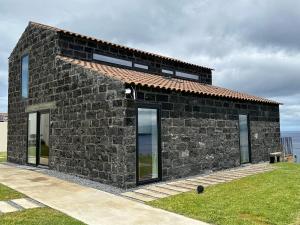 a stone house with glass doors on a field at João de Oliveira casas de campo in Santo António