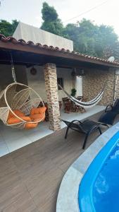 une maison avec un hamac sur une terrasse avec une piscine dans l'établissement Casa de Férias á 400m pra Praia de Cabo Branco, à João Pessoa