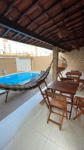 若昂佩索阿的住宿－Casa de Férias á 400m pra Praia de Cabo Branco，一个带游泳池的庭院内的吊床和椅子