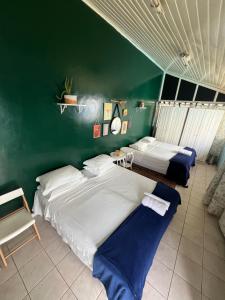 2 camas en una habitación con una pared verde en happiness house/ casa da felicidade, en Cuiabá