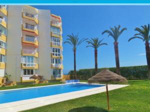 a hotel with a swimming pool and palm trees at Apartamento TORRESOL NSFA - TORRECILLA, NERJA - studio in Nerja