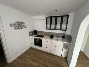 a small kitchen with white cabinets and a sink at Zentrale, stilvolle Wohnung in Lübeck