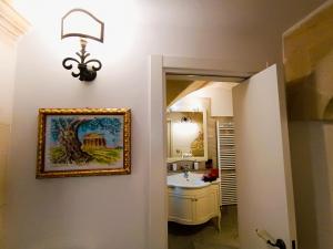 a bathroom with a sink and a painting on the wall at La Carosa Suite in Oria +24 photos
