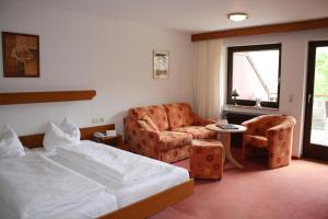 a hotel room with a bed and a couch and a chair at Hotel-Restaurant Kohlenbacher-Hof in Waldkirch