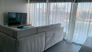 a living room with a couch and a television at Green Coast Apartment with Pool in Palasë