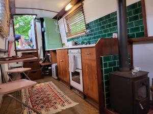 a kitchen with a stove and green tile at Unique Canal Boat in London Centre for Family & Friends in London