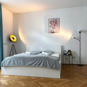 a white bedroom with a bed and a painting on the wall at Central Mariahilfer Apartment 5 min to the Schönbrunn Palace and City shopping center in Vienna