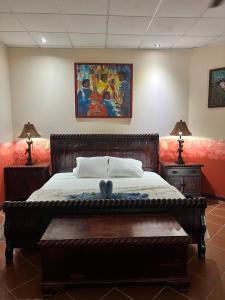 ein Schlafzimmer mit einem Bett, zwei Lampen und einem Gemälde in der Unterkunft Chosa Manglar Suites in Puerto Jiménez