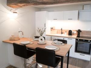 a kitchen with a wooden table and black chairs at L'Escapade, spacieux duplex in Crémieu