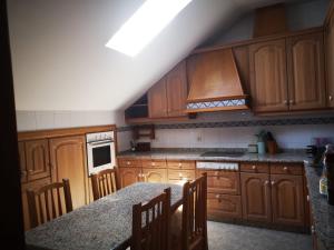 a kitchen with wooden cabinets and a table with chairs at Villa Papona - Ático ,parking in Moaña