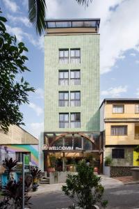 un edificio alto y verde con un letrero. en Wellcomm Spa & Hotel, en Medellín
