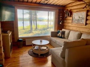 un soggiorno con divano e tavolo di Kaupinmaja, Ylläs - Log Cabin with Lake and Fell Scenery ad Äkäslompolo