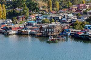 una pequeña ciudad junto al agua con casas y un barco en Palafito 1326 Hotel Boutique Chiloé en Castro