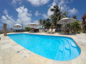 a blue swimming pool with chairs and umbrellas at Lumar Hotel PontaNegra in Natal
