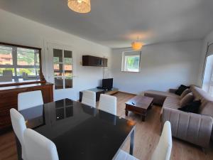 a living room with a black table and white chairs at Chalet con WIFI , PS4 , garaje, 5 dormitorios, 3 baños, Santiago de Compostela in Santiago de Compostela