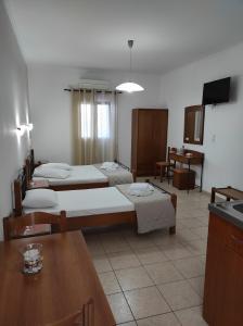 a room with four beds and a table and a kitchen at Vythos in Adamas