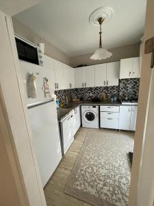 a kitchen with white cabinets and a washer and dryer at ERDEK in Erdek