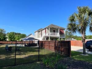 a fence in front of a house with a palm tree at Murrels Inlet House Private Heated Saltwater Pool in Myrtle Beach