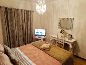 a bedroom with a bed and a television and a chandelier at Caroça House in Nazaré