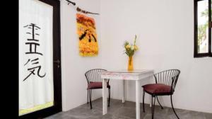 a white table with two chairs and a vase with flowers at Acogedora suite con bonito jardin in Cozumel