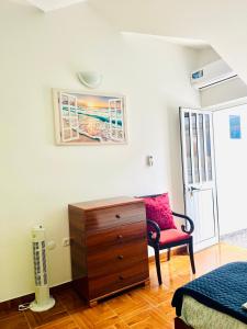 um quarto com uma cómoda e uma cadeira vermelha em Casa BB&Djassi em Ponta do Sol