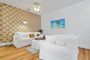sala de estar con muebles blancos y ventilador de techo en Casa Lovett - Tropical Bungalow, en St. Augustine
